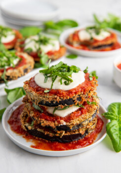 Eggplant Parmesan topped with mozzarella, sauce and basil stacked on a plate