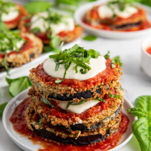 Eggplant Parmesan topped with mozzarella, sauce and basil stacked on a plate