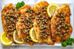 Chicken piccata on a serving platter with capers and lemons