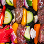 Shish kabobs in an air fryer with a basting brush.