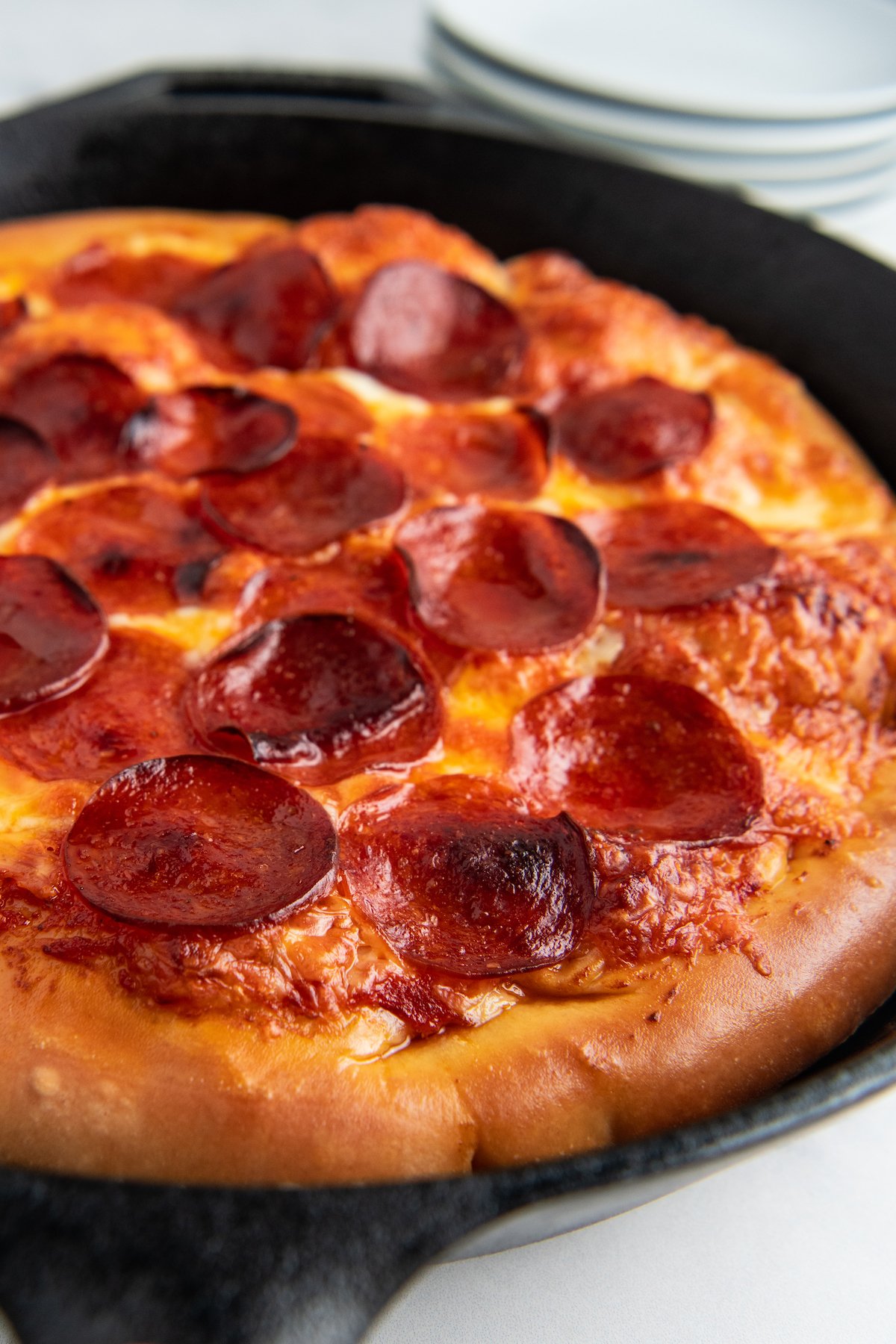 Pulled out view of a cast-iron pepperoni pizza
