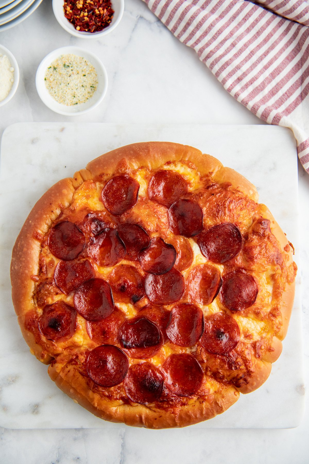 Round pepperoni pizza on a marble cutting board