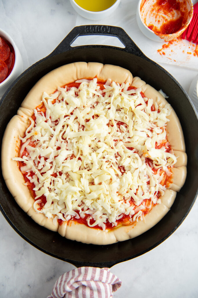 Cast Iron skillet with pizza dough, sauce and cheese