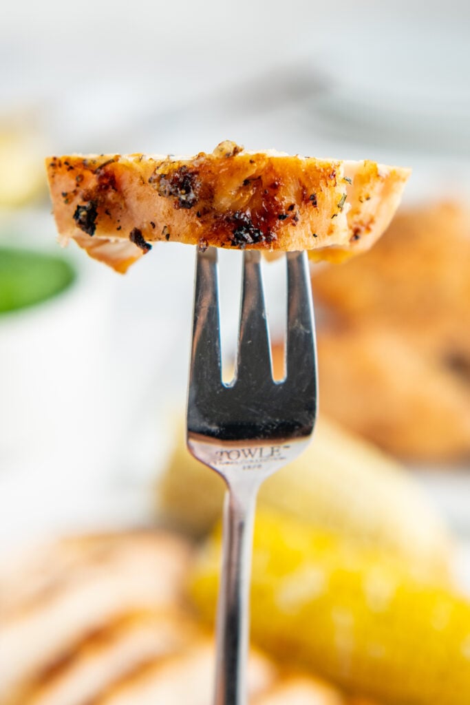 A silver fork with a piece of grilled chicken