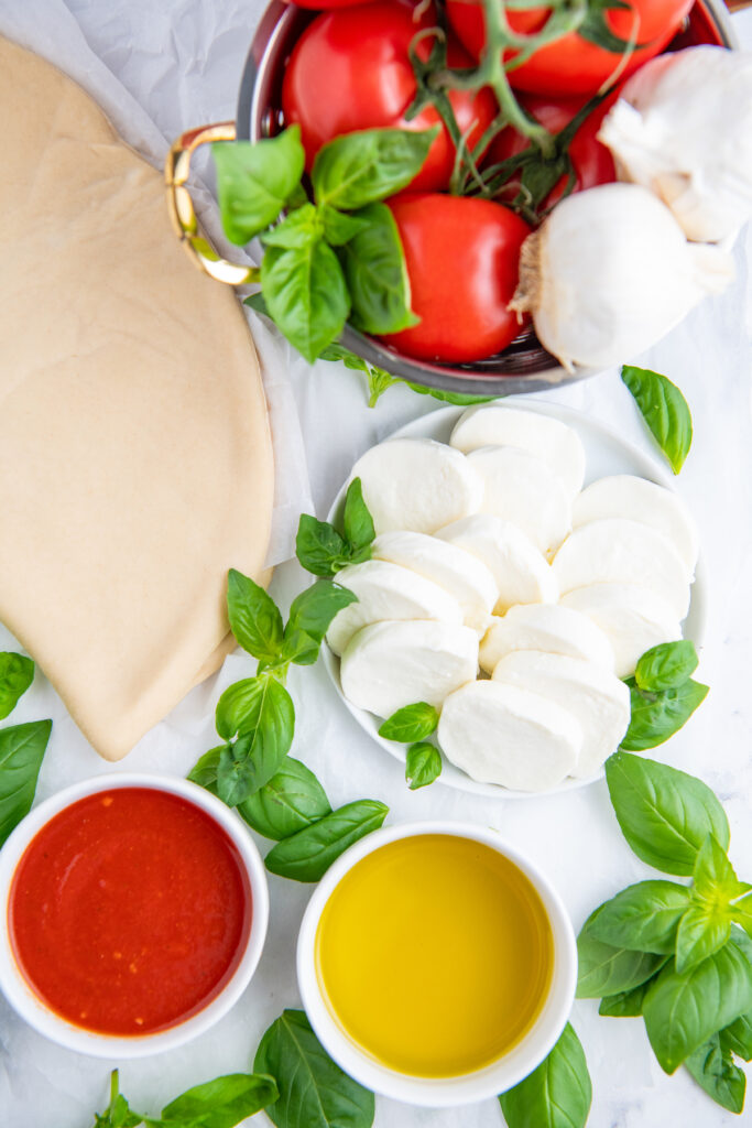 Pizza dough, fresh basil, olive oil, tomato, mozzarella cheese and pizza sauce 