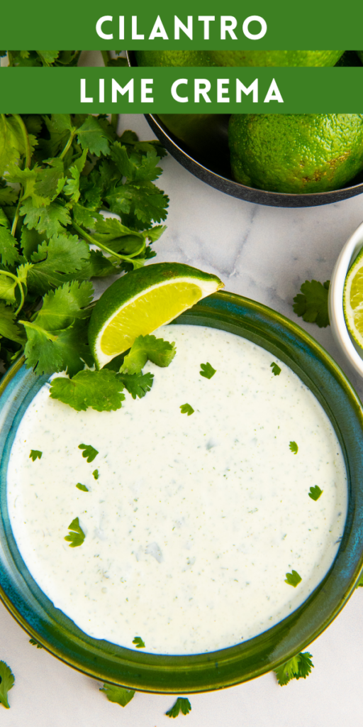 Cilantro cream sauce in a green bowl with lime wedges and fresh cilantro