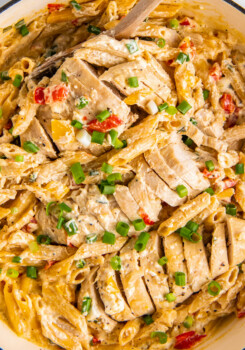 A sliced chicken breast is in a pot with creamy cajun pasta.