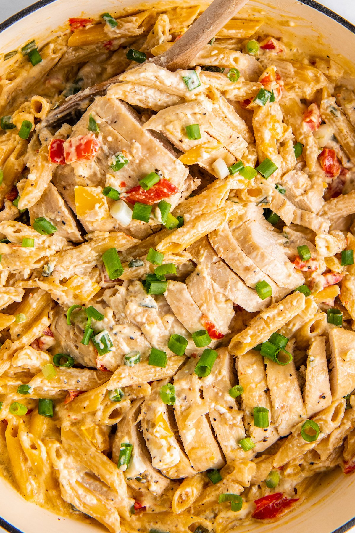 A sliced chicken breast is in a pot with creamy cajun pasta. 