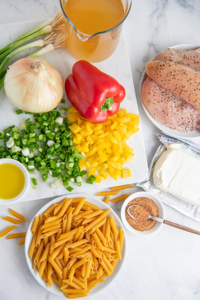The ingredients for Cajun Chicken Pasta are placed on a white surface.