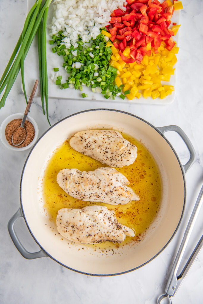 A white pot has three chicken breasts in it.