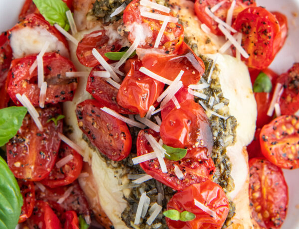 Tomatoes and grilled chicken are topped with shredded cheese.