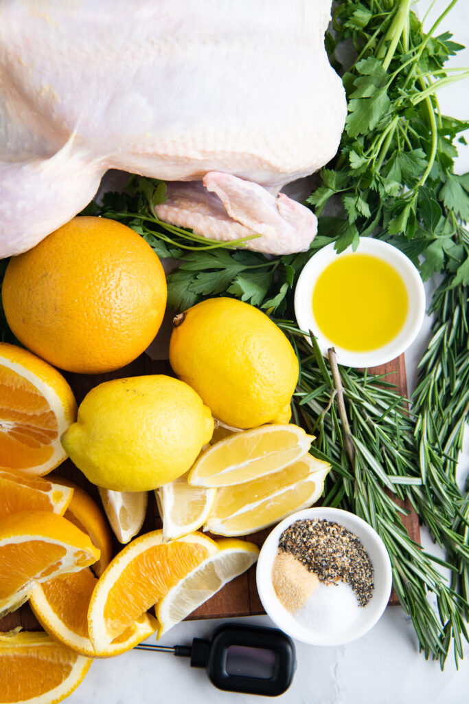 The ingredients for roasted chicken are placed on a white surface. 