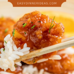 Orange chicken with rice on chopsticks.
