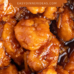 Up close image of chicken nuggets tossed in an orange sauce.