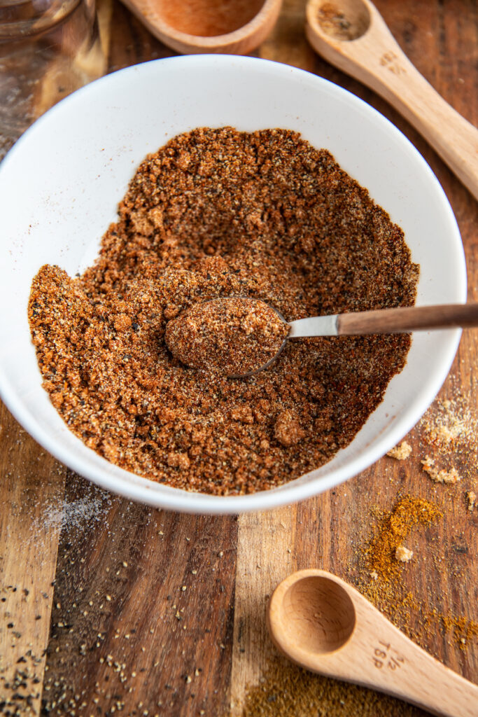 Up close image of seasonings in a white bowl with a spoon.