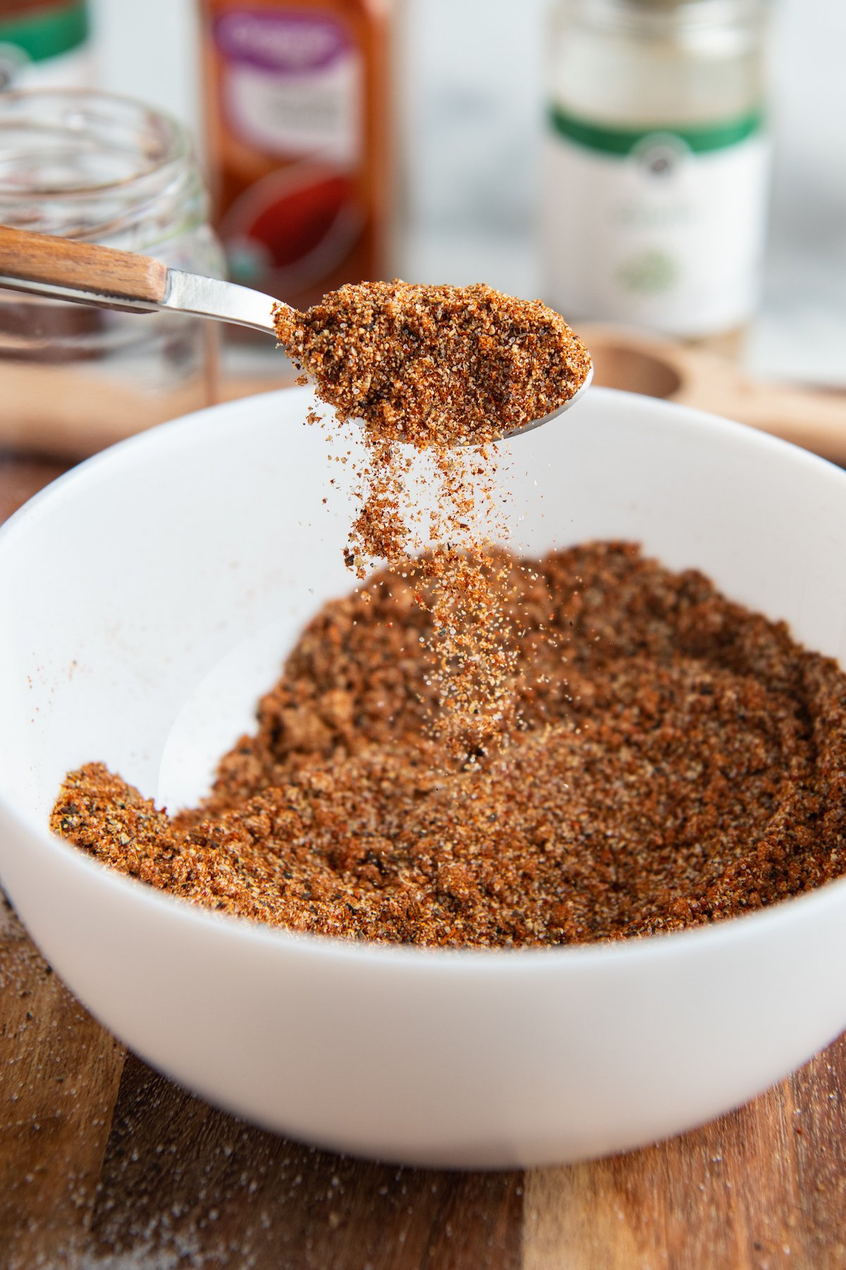 Image of a metal spoon pouring spices into a bowl. 