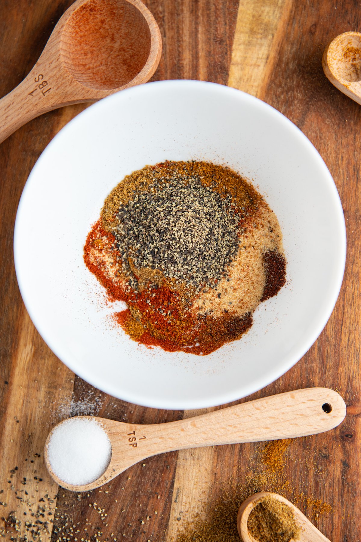 Seasonings in a white bowl on a wood cutting board. 