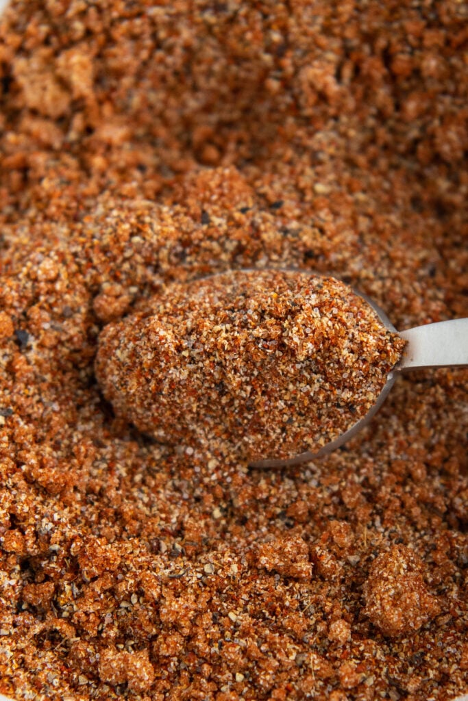 Up close image of a spoon holding spices of a dry rub for ribs.