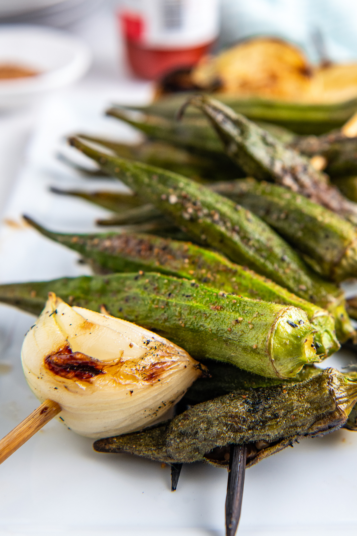 up close picture of okra and onion grilled on a skewer. the food is done and a little charred 