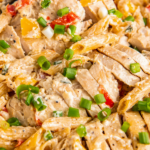 Overhead image of cajun chicken pasta in a pot with green onions on top.