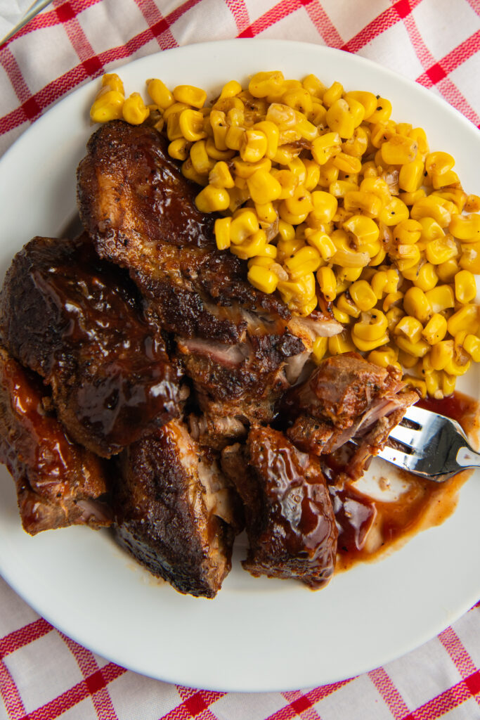 white plate full of ribs and corn