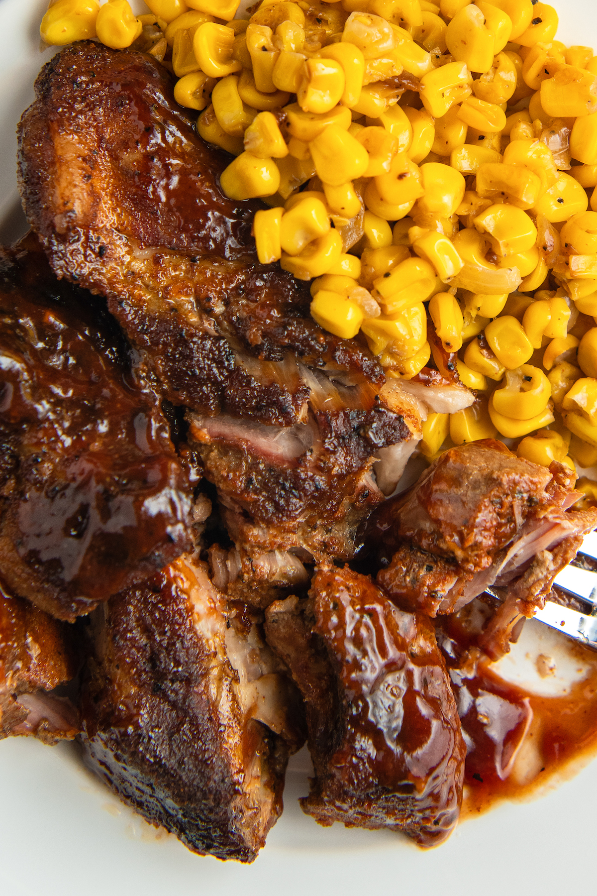ribs covered in BBQ sauce with corn