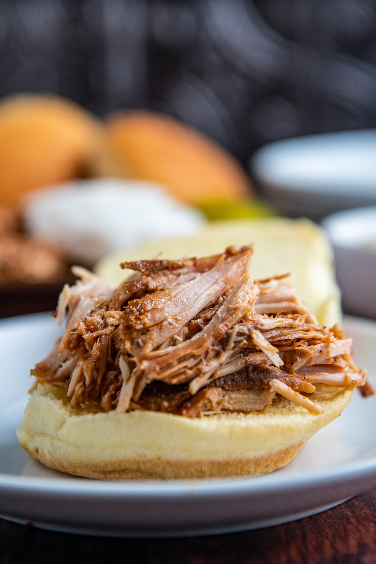 Shredded crockpot pulled pork on sandwich bread and on a white plate.