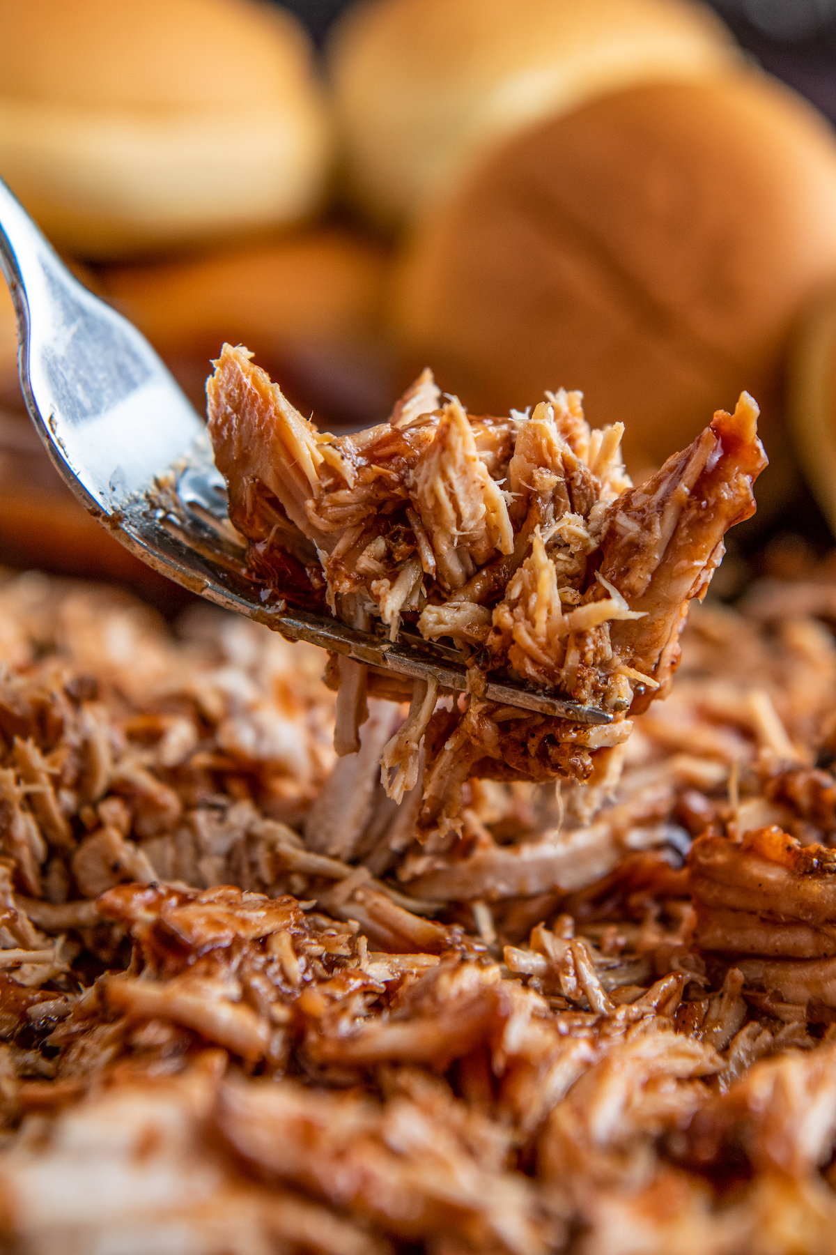 Shredded crockpot dr pepper pulled pork on a fork with bbq sauce.