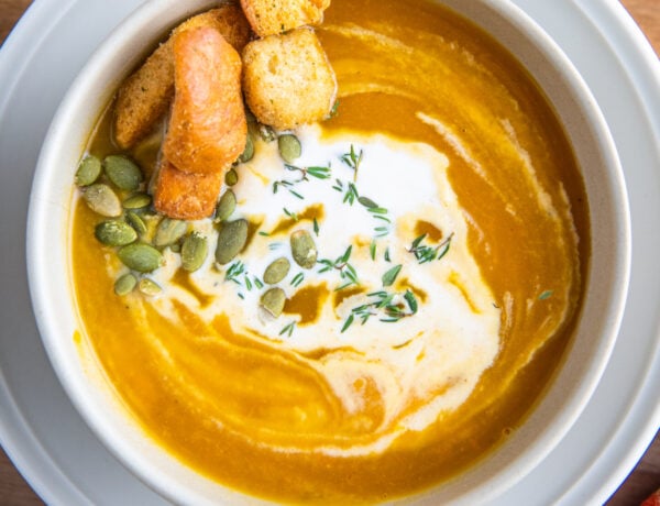 A bowl of butternut squash soup with cream on top and a fall napkin.