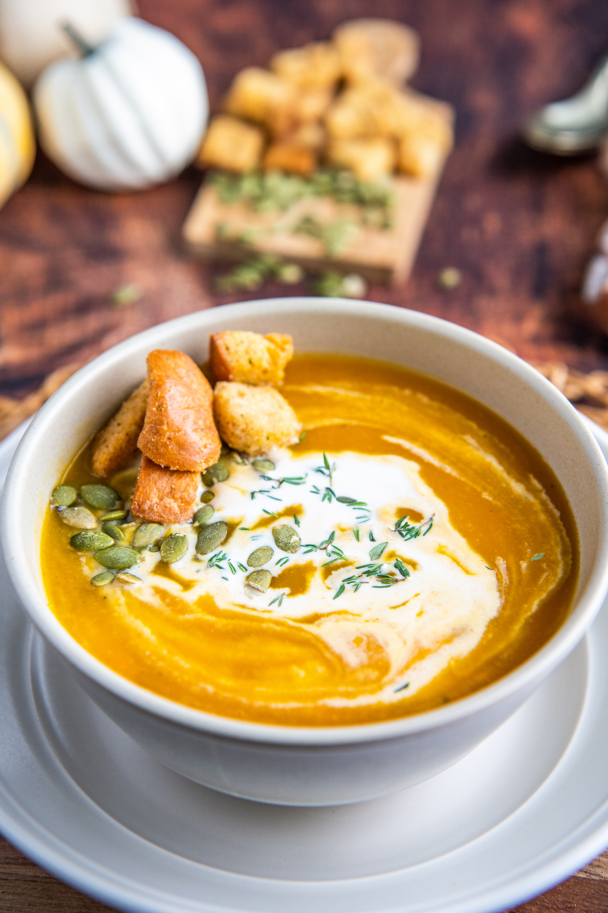 Butternut squash in a bowl with cream and pumpkin seeds on top.