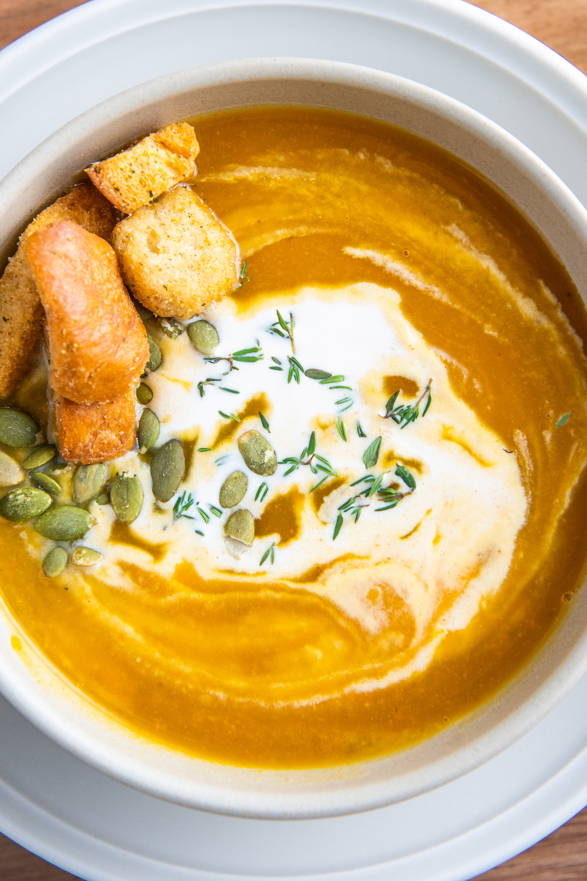 Up close image of a bowl of butternut squash soup with cream on top and croutons.