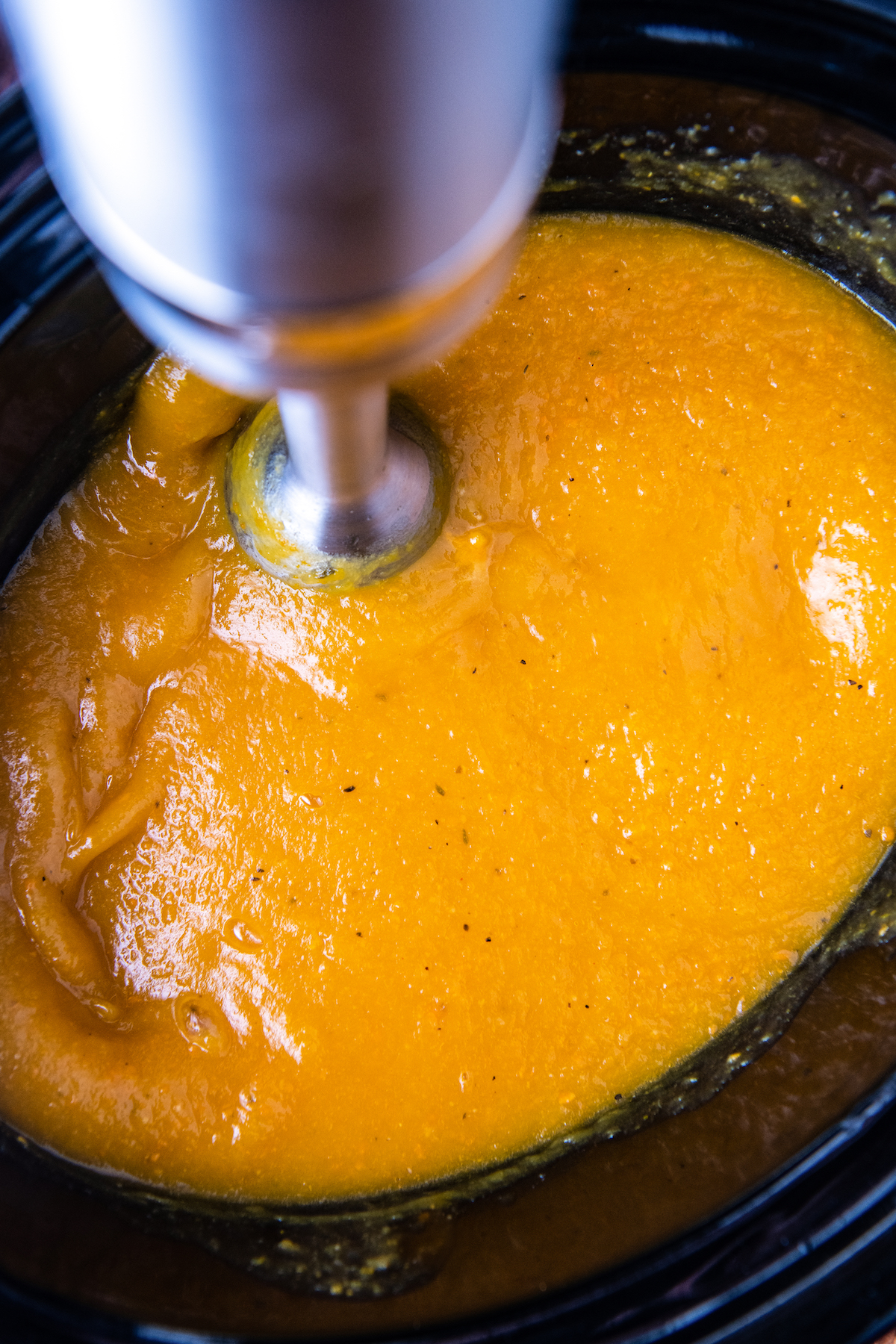 Butternut squash being pureed in a crockpot insert.