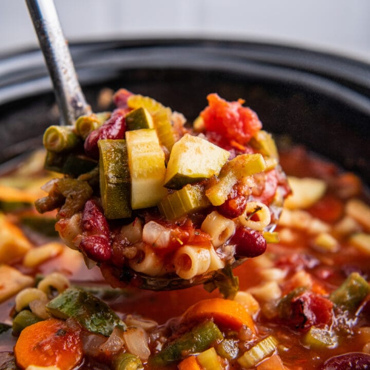 A ladle scooping up a serving of crockpot minestrone soup.