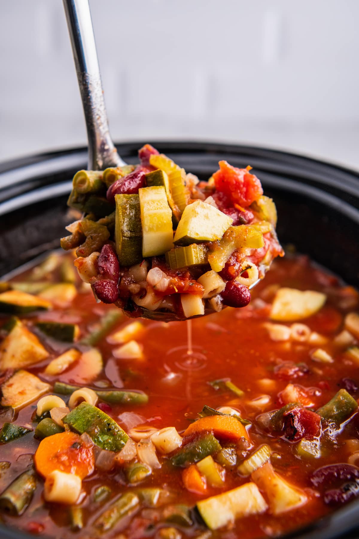 A ladle with a spoonful of minestrone soup from the crockpot.