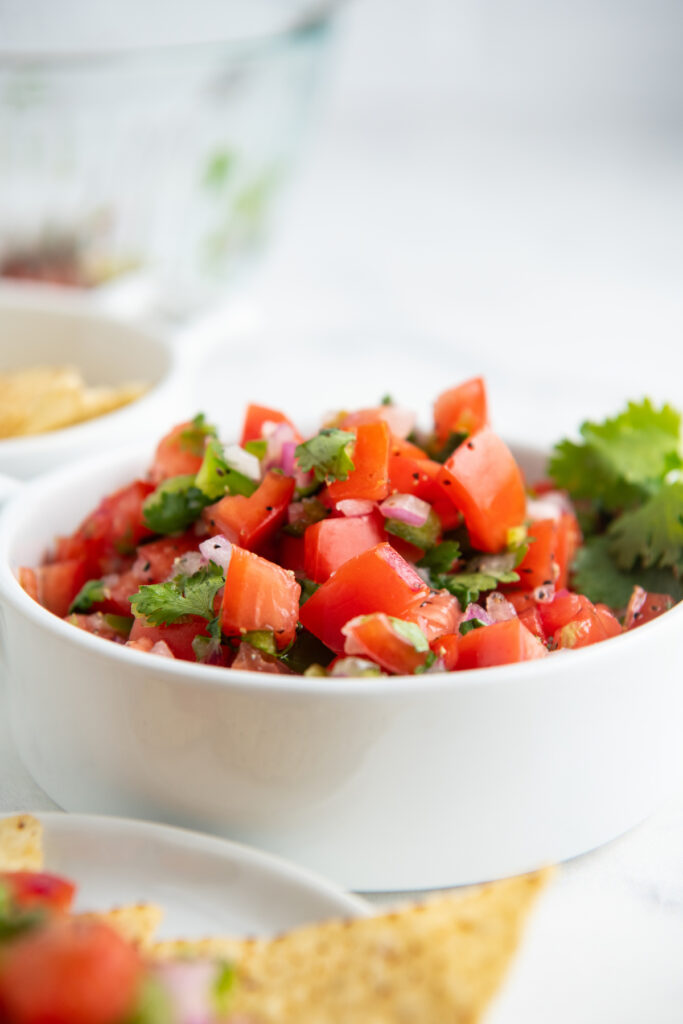 Fresh homemade pico de Gallo in a white bowl with cilantro on top.