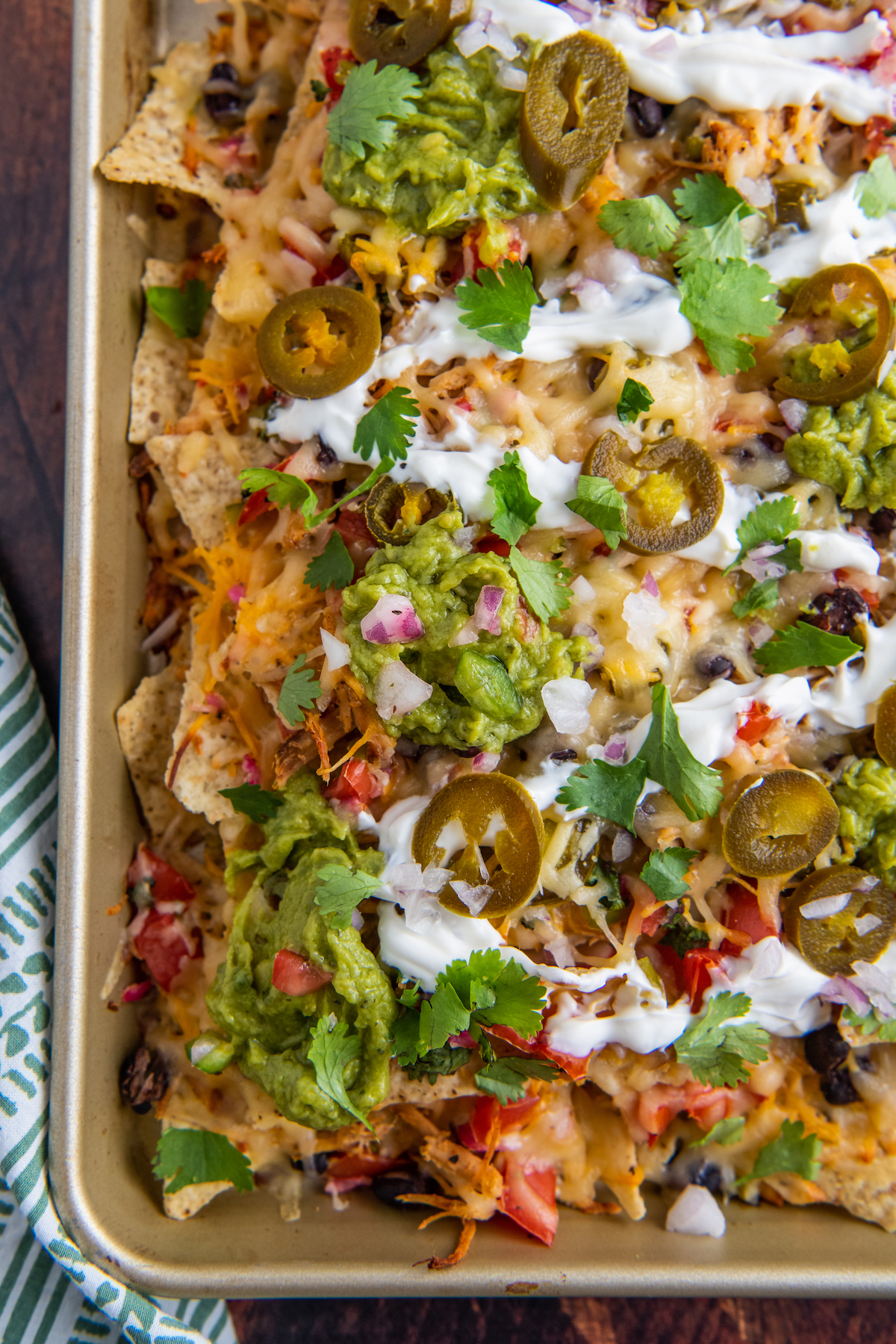 Overhead view of pulled pork nachos on a sheet pan with a napkin.