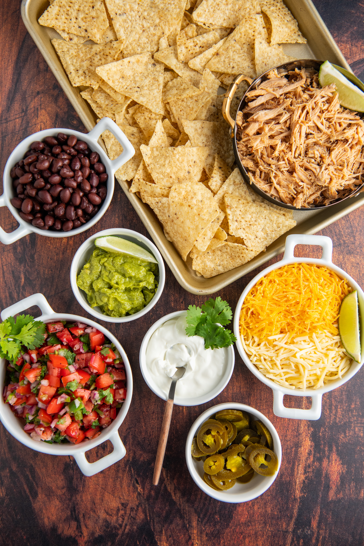 Ingredients for pulled pork nachos in white bowls.