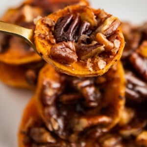 Candied sweet potato on a fork with pecans and brown sugar and cinnamon.