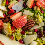 Overhead view of Shaved Brussel Sprout Salad with fresh citrus and apple slices on top.