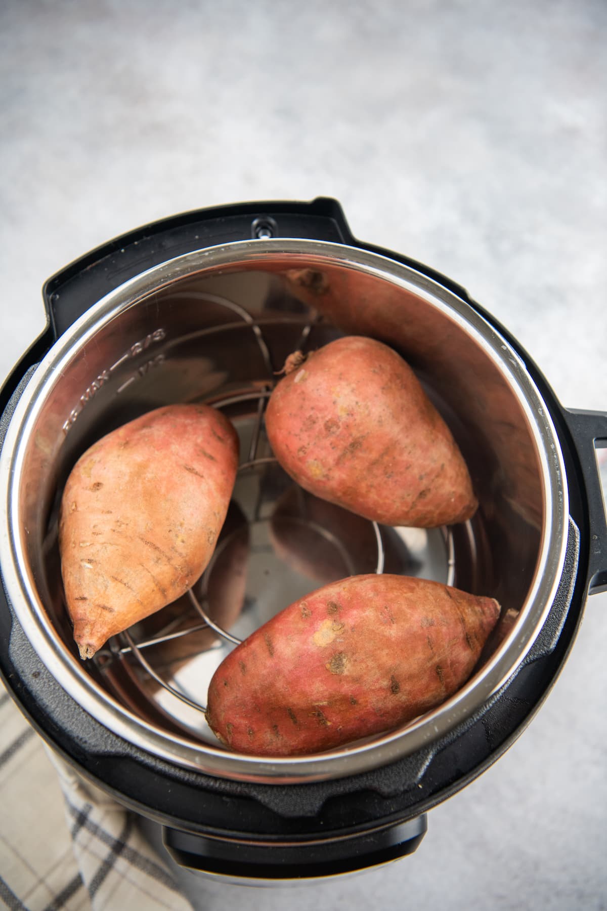 Three sweet potatoes in an instant pot sitting on a trivet.