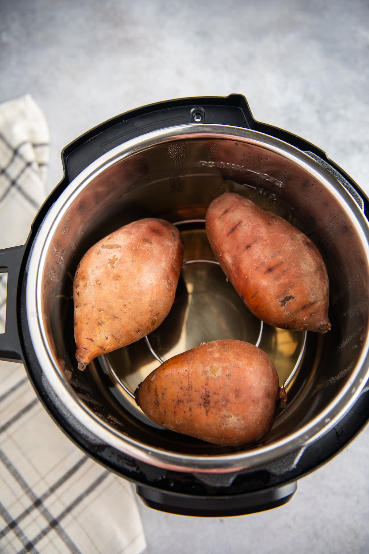 Overhead image of three cooked sweet potatoes inside an instant pot.