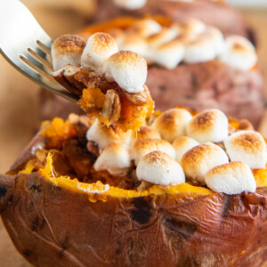Up close image of loaded sweet potato with a fork picking up some sweet potato and marshmallows.