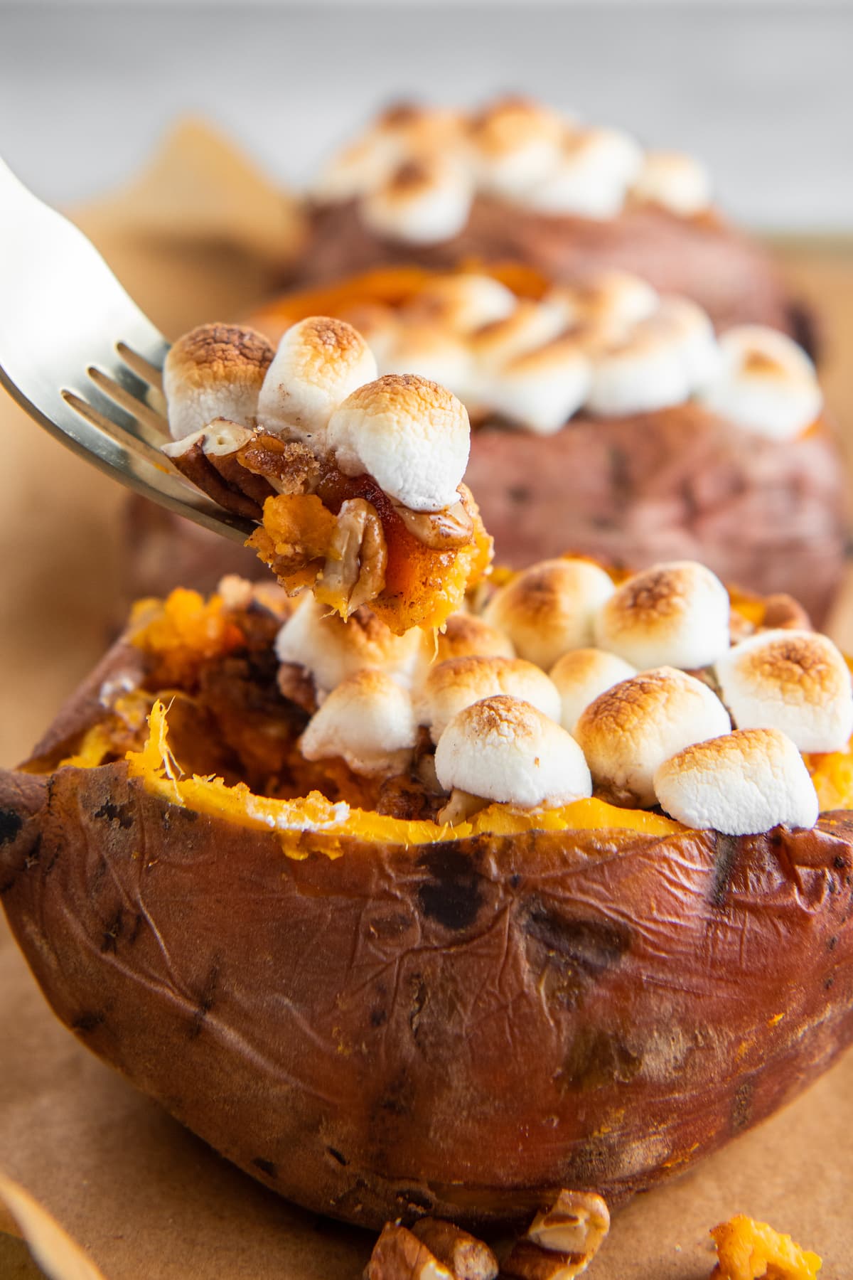 Up close image of loaded sweet potato with a fork picking up some sweet potato and marshmallows.