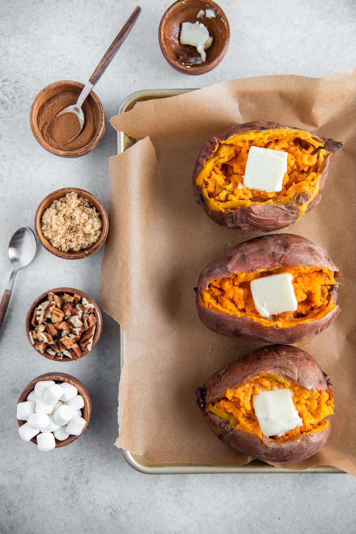 Sweet potatoes on parchment paper with butter added to them.