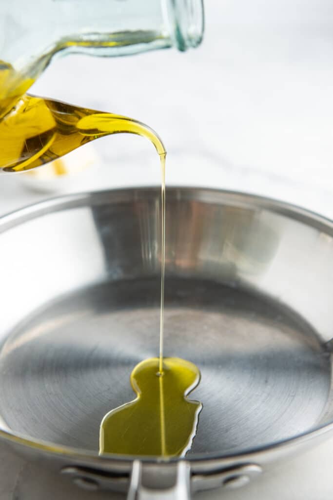 Olive oil being poured into a skillet.