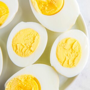 Overhead image of hard boiled eggs cooked in an air fryer on a white plate.