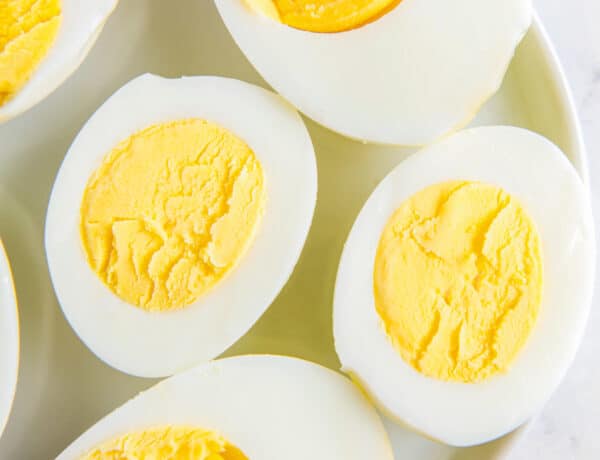 Overhead image of hard boiled eggs cooked in an air fryer on a white plate.