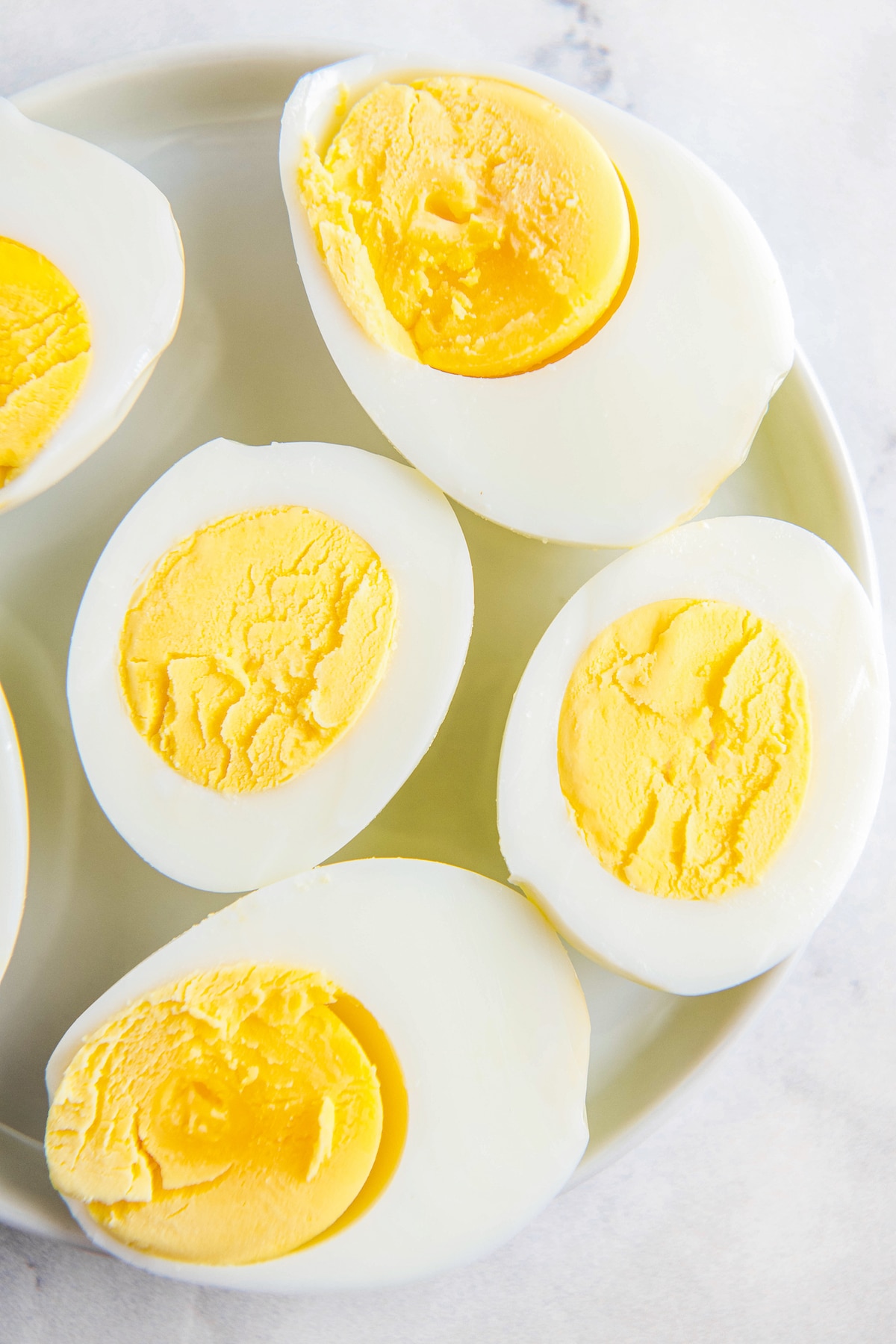 Overhead image of hard boiled eggs cooked in an air fryer on a white plate.