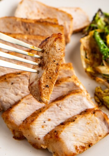 Sliced pork chop being picked up by a fork.