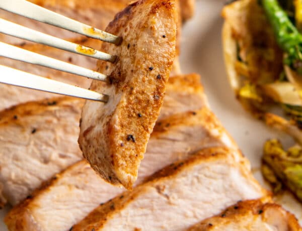 Sliced pork chop being picked up by a fork.